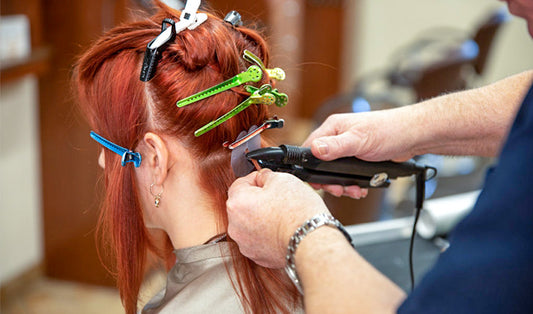 stylist applying keratin hair extensions to client hair